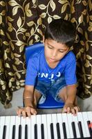 asiático chico jugando el sintetizador o piano. linda pequeño niño aprendizaje cómo a jugar piano. niño manos en el teclado interior. foto