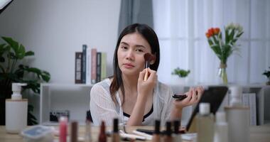 hermosa joven asiático mujer blogger muestra cómo a hacer arriba y utilizar productos cosméticos foto