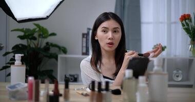 Beautiful young Asian woman blogger shows how to make up and use cosmetics photo