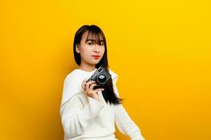 Female photographer with camera young women love taking pictures camera lover taking pictures in the yellow studio photo