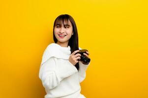 Female photographer with camera young women love taking pictures camera lover taking pictures in the yellow studio photo