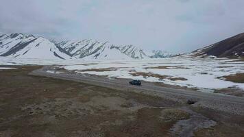 le route parmi neigeux montagnes et une qui passe voiture, aérien vue video