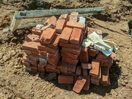 A pile of bricks on the construction site. Construction of a new house. A pile of building materials, a stack of red bricks for construction is put together. photo