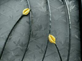 Abstract metal background with yellow leaves on a black background. Abstract background with leaves on the iron fence. Detail of a forged metal fence with yellow leaves on it. photo