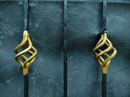 Close-up of an iron fence with golden ornament on a black background. Old metal gate with a forged pattern. Metal fence with forged elements. photo