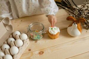 Cute little girl in a cotton dress at home in a wooden kitchen prepares an Easter cake photo