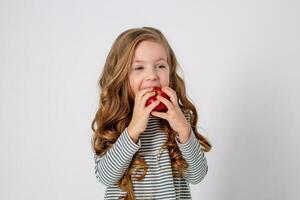 portrait of a small happy girl of Slavic appearance eating a red apple. place for text photo