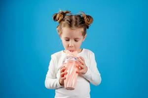 portrait of a small happy girl of Slavic appearance drinking a cocktail of berries. place for text photo