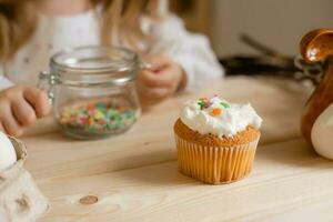 Cute little girl in a cotton dress at home in a wooden kitchen prepares an Easter cake photo