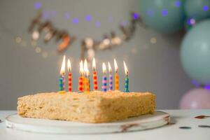 cute little girl blows out candles on a birthday cake at home against a backdrop of balloons. Child's birthday photo