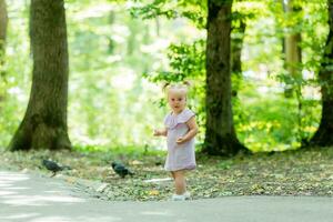 un contento pequeño niña de eslavo apariencia camina en el parque en el lugar.de.verano para texto foto