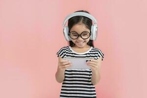 Little girl play phone mobile. Isolated on pink background photo