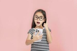 Little girl play phone mobile. Isolated on pink background photo