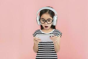 Little girl play phone mobile. Isolated on pink background photo