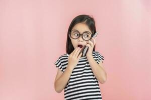 Little girl play phone mobile. Isolated on pink background photo