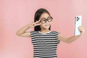 Little girl play phone mobile. Isolated on pink background photo