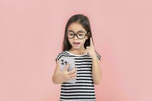 Little girl play phone mobile. Isolated on pink background photo