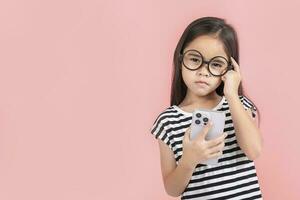 Little girl play phone mobile. Isolated on pink background photo