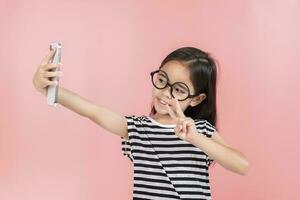 Little girl play phone mobile. Isolated on pink background photo