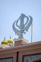 Khanda sij santo religioso símbolo a gurudwara Entrada con brillante azul cielo imagen es tomado a hermana marihuana sahib gurudwara en Chandi choc, opuesto rojo fuerte en antiguo Delhi India foto