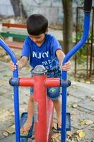 asiático chico haciendo rutina ejercicio en sociedad parque durante el Mañana tiempo. linda pequeño niño ejercicio y gimnasio a mantener él mismo ajuste para vida. niño ejercicio al aire libre disparar foto