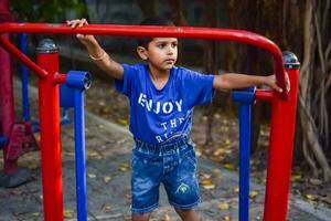 Asian boy doing routine exercise in society park during the morning time. Cute little kid exercise and gym to keep himself fit for life. Child's exercise outdoor shoot photo