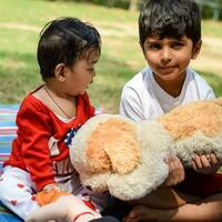 Two happy boys in society park, happy Asian brothers who are smiling happily together. Brothers play outdoors in summer, best friends. Toddler baby boy playing with his happy brother in the garden photo