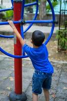 Asian boy doing routine exercise in society park during the morning time. Cute little kid exercise and gym to keep himself fit for life. Child exercise outdoor shoot photo