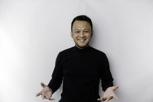 Young Asian man wearing black t-shirt presenting an idea while looking smiling on isolated white background photo