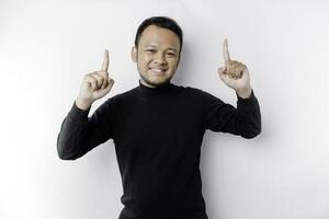 Excited Asian man wearing black shirt pointing at the copy space on top of him, isolated by white background photo