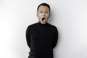 Shocked Asian man with his mouth wide open wearing black shirt, isolated by a white background photo