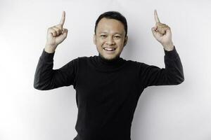 Excited Asian man wearing black shirt pointing at the copy space on top of him, isolated by white background photo