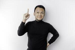 Excited Asian man wearing black shirt pointing at the copy space on top of him, isolated by white background photo