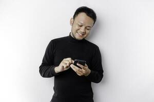 Excited Asian man wearing black shirt smiling while holding his phone, isolated by white background photo