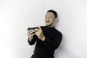 Young Asian man in casual wear is playing games with mobile phone with a white background isolated. photo