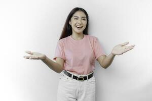 Young Asian woman wearing pink t-shirt presenting an idea while looking smiling on isolated white background photo