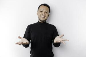 Young Asian man wearing black t-shirt presenting an idea while looking smiling on isolated white background photo