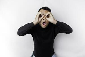 Funny obvious peeking Asian man in black shirt isolated on white background. photo