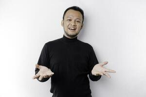 joven asiático hombre vistiendo negro camiseta presentación un idea mientras mirando sonriente en aislado blanco antecedentes foto