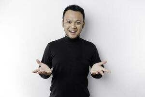Young Asian man wearing black t-shirt presenting an idea while looking smiling on isolated white background photo