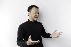 Young Asian man wearing black t-shirt presenting an idea while looking smiling on isolated white background photo