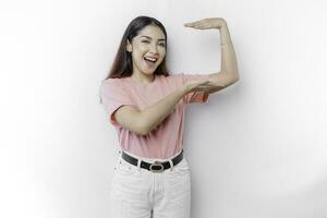 Smiling young Asian woman is standing over isolated background holding copy space imaginary on the palm to insert an ad photo