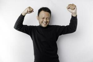 A young Asian man with a happy successful expression wearing black shirt isolated by white background photo