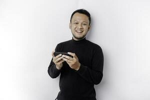 Young Asian man in casual wear is playing games with mobile phone with a white background isolated. photo