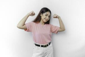 emocionado asiático mujer vistiendo un rosado camiseta demostración fuerte gesto por levantamiento su brazos y músculos sonriente con orgullo foto