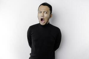 Shocked Asian man with his mouth wide open wearing black shirt, isolated by a white background photo