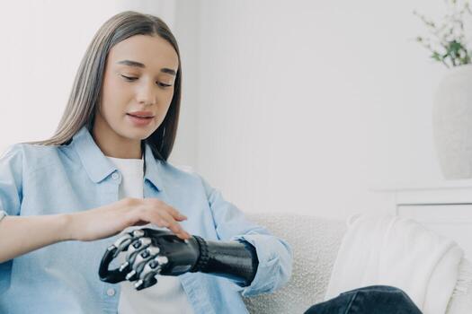 Handicapped girl is exploring her bionic arm and pressing buttons. Futuristic technology. photo
