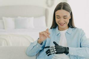 Pretty caucasian woman with artificial arm in bedroom. Engineering and technology concept. photo