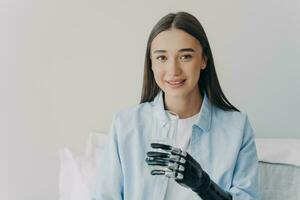 Disabled girl grasps a glass with myoelectric hand. High technology prosthesis. photo