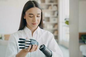 Disabled young woman is assembling bionic arm. Software and buttons, fingers and palm. photo